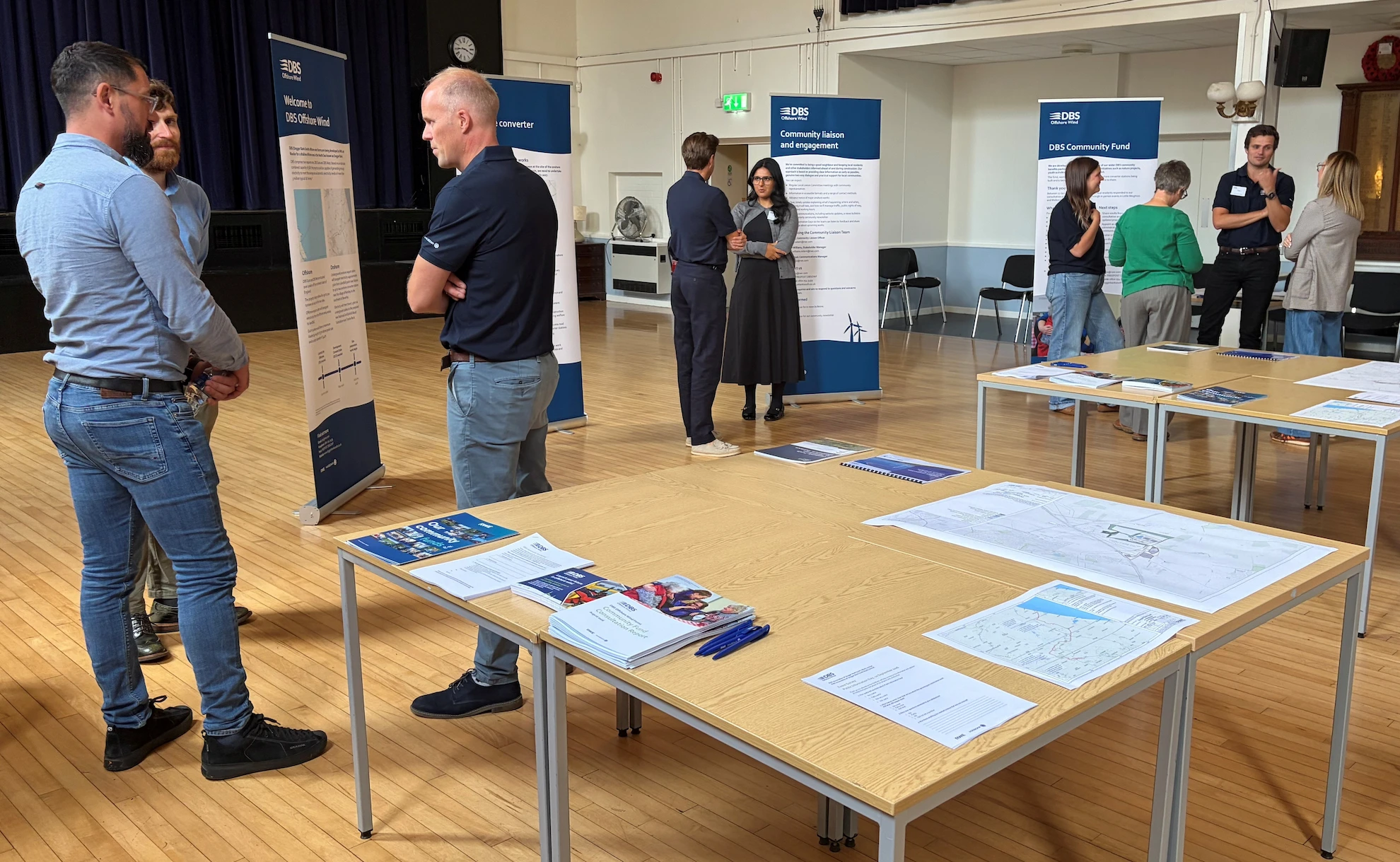 Members of the DBS project team talking with residents at Beverley Memorial Hall, with project banners and tables of maps and consultation documents.